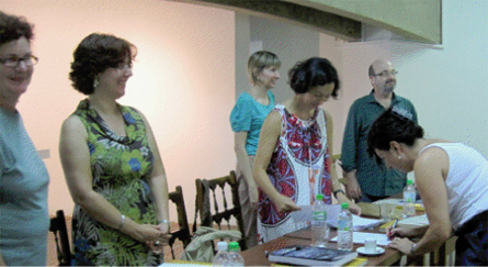 Ana Paula assinando o documento de aprovação em frente à banca de doutores (da esquerda para direita): Luise Weiss, Maria de Fatima Morethy,  Anna Paula Gouveia, Daniela Kurschat e Silvio Dworecki